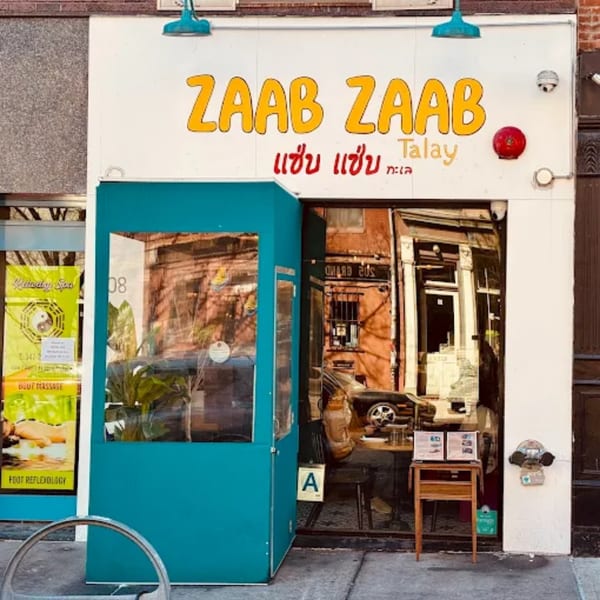 Zaab Zaab Thai restaurant storefront with a teal outdoor dining enclosure and yellow signage.